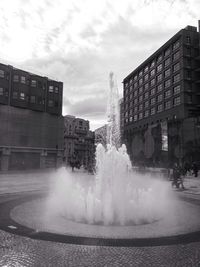 Buildings in city against cloudy sky