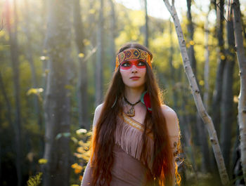 Young woman in traditional clothing looking away while standing in forest