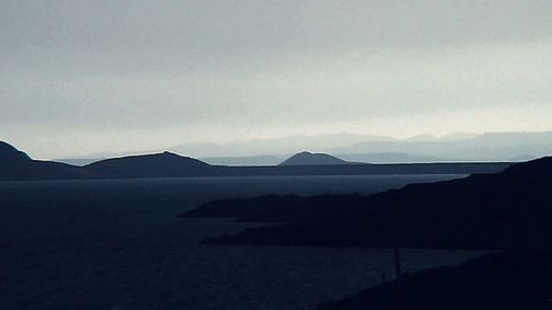 Scenic view of sea in front of mountains against sky