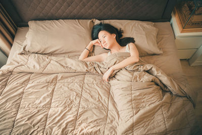 High angle view of mid adult woman lying on bed at home