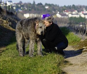 Woman kissing irish wolfhound on grassy field