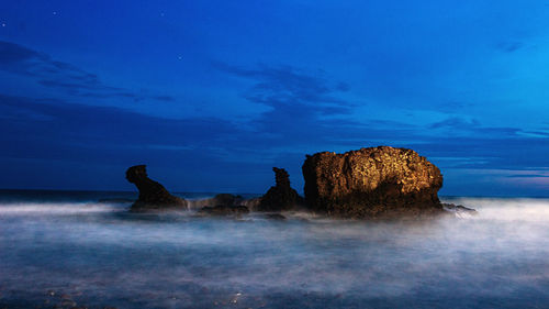 Rocks in sea against blue sky