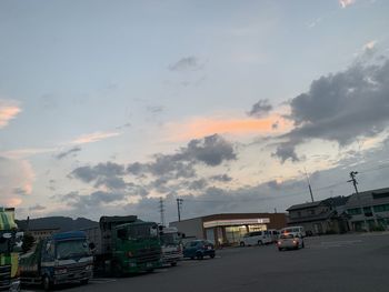 Vehicles on road against sky at sunset