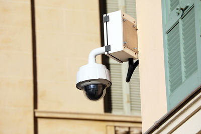 Low angle view of electric lamp against building