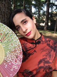 Portrait of young man against tree trunk