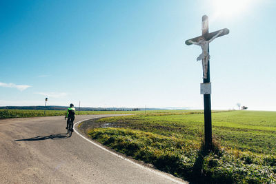 Rear view of man walking on road against sky