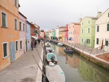 Canal amidst buildings in city against sky