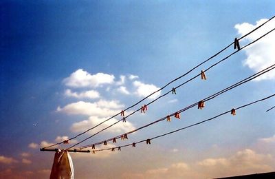 Low angle view of electricity pylon against cloudy sky