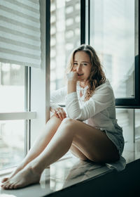 Young woman sitting on window