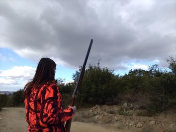 Rear view of woman holding umbrella against sky