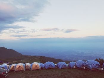Tents on mountain against sky during sunset