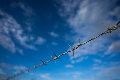 Low angle view of barbed wire against sky