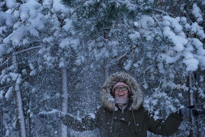 Woman enjoying while standing against snow covered trees