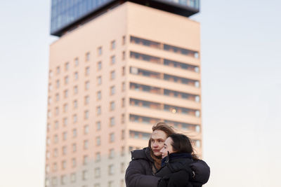 Female couple hugging in modern neighborhood