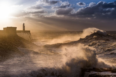 Waves splashing against cloudy sky during sunset