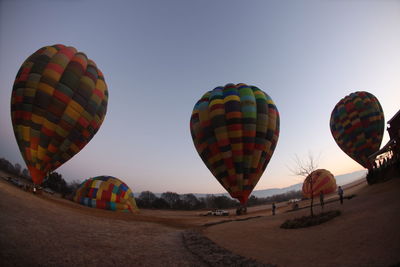 Low angle view of colorful hot air balloons on landscape against sky
