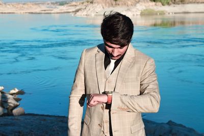 Businessman checking time against lake