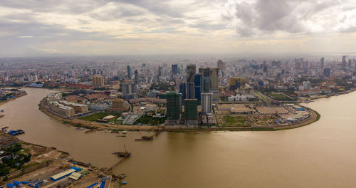 High angle view of buildings by river against sky in city