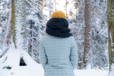 Rear view of woman standing in forest during winter