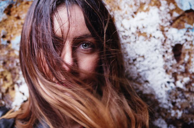 Close-up portrait of woman against weathered wall