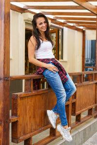 Young caucasian woman is smiling standing on porch near door of store in casual