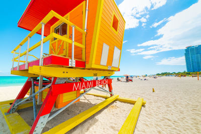 Yellow hut on beach against sky