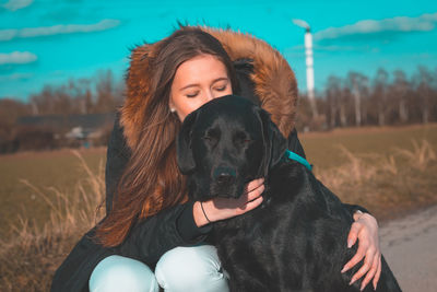 Portrait of woman with dog on roadside during winter