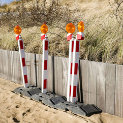 Luminous road signs leaning against a wooden barrier near the beach