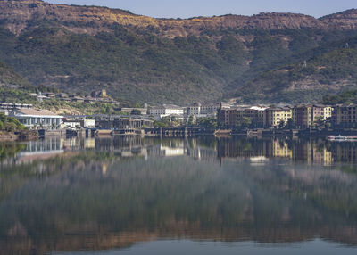 Scenic view of lake by buildings against mountain