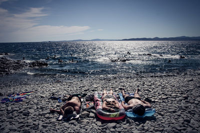 People relaxing on beach against sky