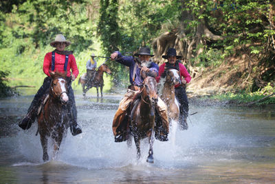 Men riding horses in river 