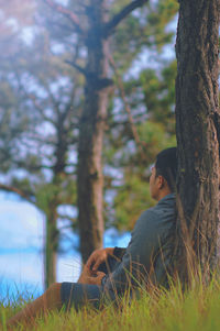 Young woman sitting on tree trunk