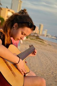Portrait of woman playing guitar on beach