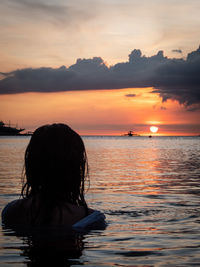 Rear view of woman looking at sea during sunset