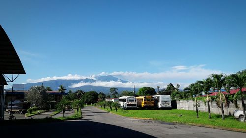 Road by houses against blue sky