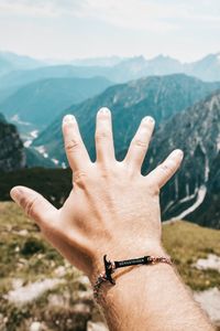 Midsection of human hand against mountain