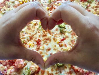 Close-up of hand holding pizza heart