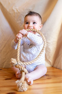 Cute baby girl sitting on wooden floor at home