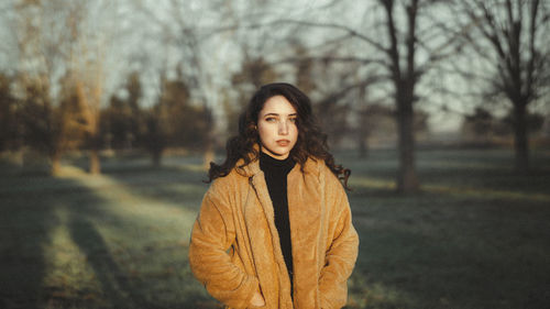 Portrait of young woman standing in park during winter