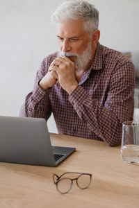 Mature businessman using laptop while sitting at table