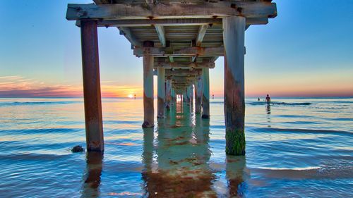 Pier on sea against sky at sunset