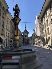 Statue amidst street and buildings against clear sky