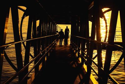 Rear view of silhouette people walking on footbridge