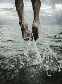 Low section of person jumping in sea