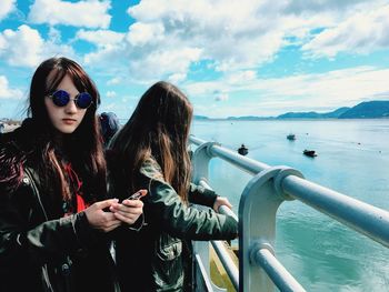 Friends standing on ship against cloudy sky