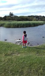 Full length of woman standing on grass by lake