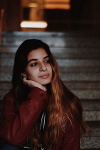 Thoughtful young woman sitting outdoors at night