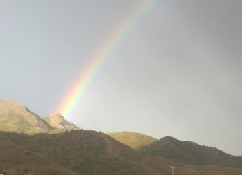 Scenic view of rainbow over mountains against sky