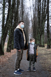 Full length of friends standing on street amidst trees in forest