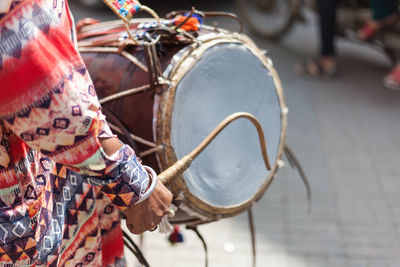 Man in traditional lahori dress beating dhol on street in lahore city.